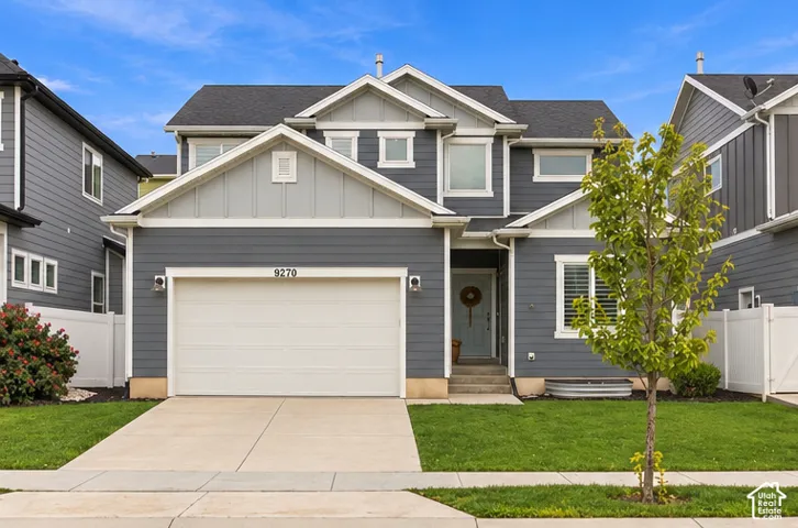 Two-story residence featuring horizontal lap siding, a front-facing attached two-car garage, multiple gables, and a concrete driveway. This image has been digitally altered to remove dumpsters and a vehicle from view. Real-time conditions may vary.