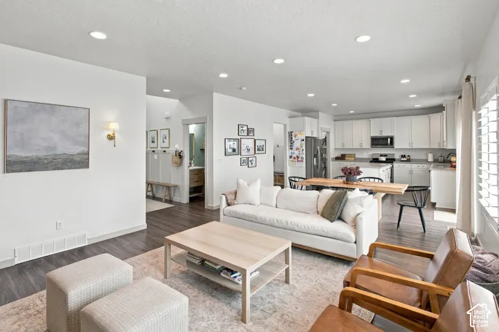 Open-concept interior featuring wood-finish flooring, recessed lighting, white cabinetry, and wall-mounted sconce lighting
