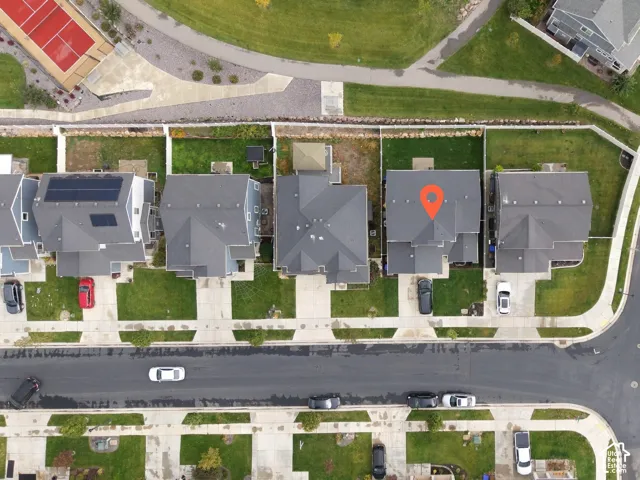 Aerial view of a residential property featuring a concrete driveway, a multi-level asphalt shingle roof, a fenced backyard, and a manicured lawn