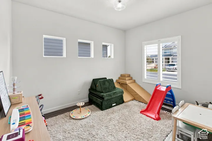 Room featuring wood-finish flooring, plantation shutters, three square accent windows, and a flush-mount ceiling fixture