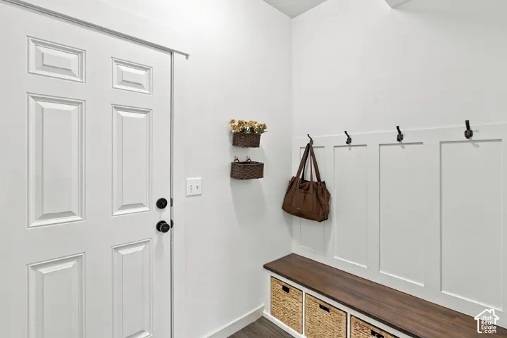 Entry area featuring a paneled door, built-in mudroom bench with a wood-finish surface, board-and-batten wall detailing, and matte black hardware