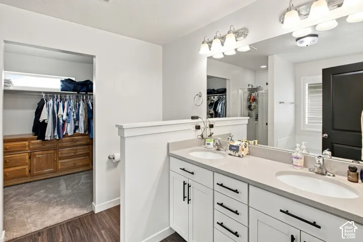 Dual-vanity cabinet with white shaker-style cabinetry, matte black hardware, stone-composite countertop, and two integrated oval sinks under a full-width vanity mirror