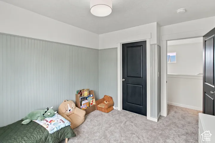 Interior space featuring beadboard wall paneling, neutral carpeting, two black paneled doors, and a flush-mount drum light fixture