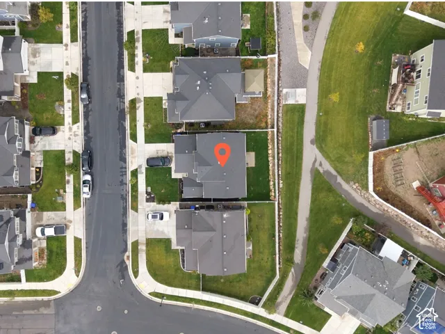 Aerial perspective of a detached residential property featuring a multi-gable roofline, a paved concrete driveway, and a fenced backyard