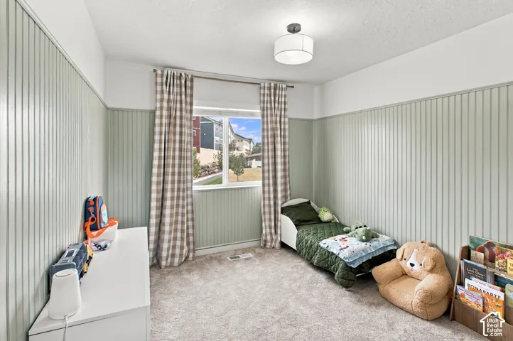 Interior room featuring floor-to-ceiling vertical beadboard wainscoting, neutral carpeting, and a modern drum-style flush-mount light fixture