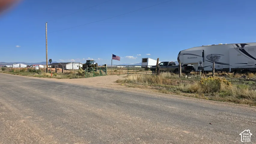 Expansive rural acreage featuring a perimeter metal gate, gravel access point, and mountain backdrop