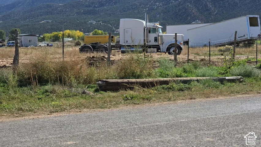Expansive lot featuring barbed wire fencing and prominent mountain terrain backdrop