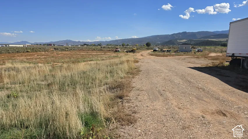 Expansive level acreage featuring a dirt access road and mountain range backdrop