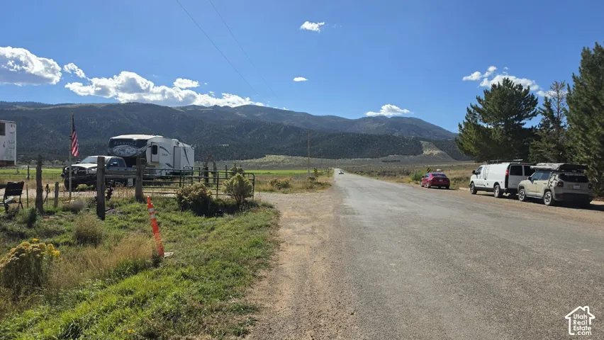 Expansive acreage featuring mountain range backdrop, native scrub vegetation, and gravel road access