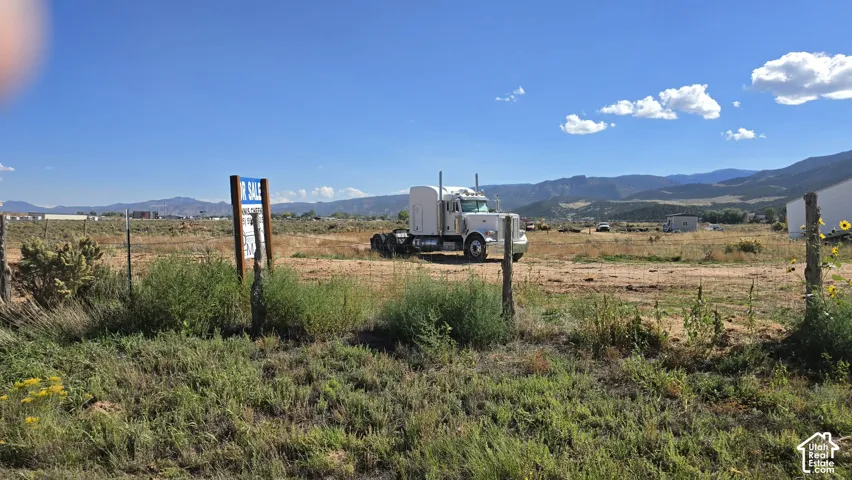 Expansive vacant land featuring a perimeter wire fence and unobstructed mountain range backdrop