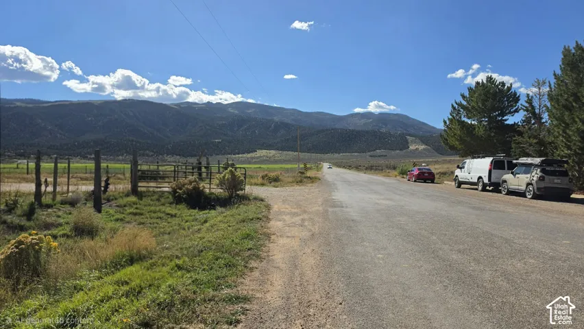 Expansive land featuring mountain scenery, mature trees, and wire perimeter fencing