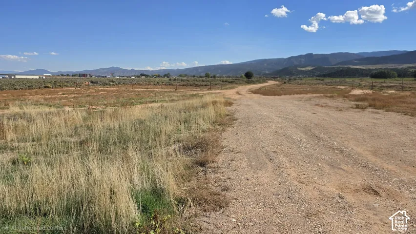 Expansive land parcel featuring native grasses, a natural dirt path, and prominent mountain backdrops