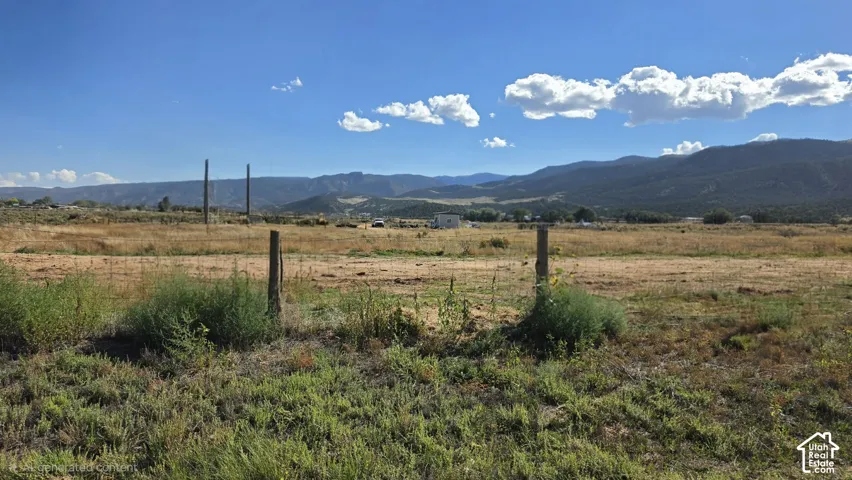 Expansive acreage featuring native grasses, wood-post fencing, and prominent mountain scenery