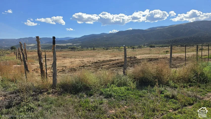 Expansive acreage featuring rugged mountain backdrops, natural terrain, and perimeter post-and-wire fencing