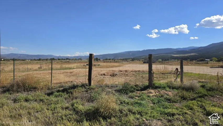 Open lot featuring wire fencing, wooden posts, and mountainous terrain
