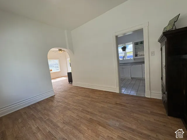 Interior space featuring wood-finish flooring, an arched architectural opening, and white trim molding throughout