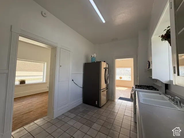 Kitchen featuring ceramic tile flooring, built-in cabinetry, dual-basin sink, gas range, and refrigerator