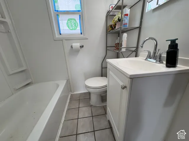 Bathroom featuring a white vanity cabinet with a drop-in sink, chrome faucet, tile flooring, and a tub-shower combination unit
