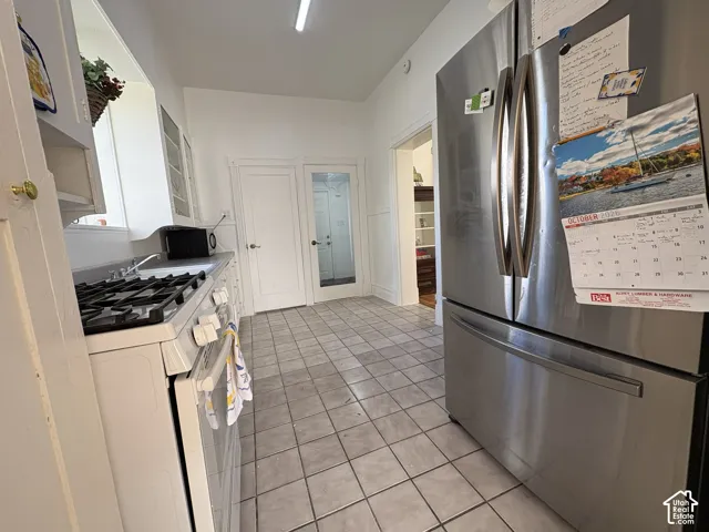 Kitchen featuring ceramic tile flooring, stainless steel French door refrigerator, white gas range, and a glass-paneled interior door