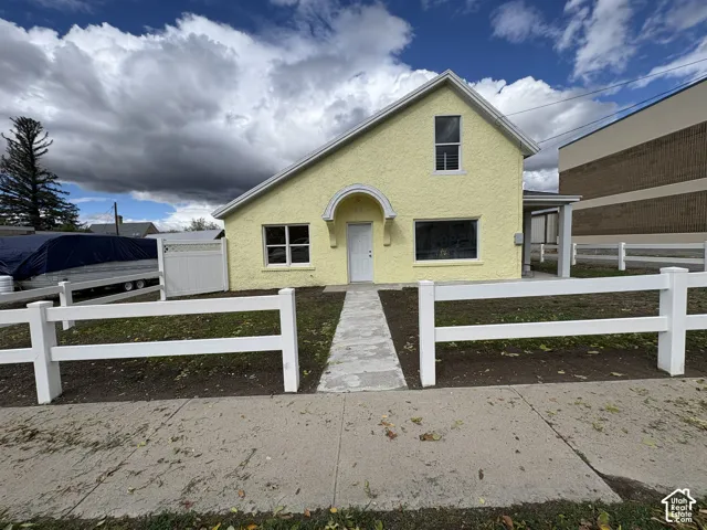 Exterior featuring a textured stucco finish, a covered arched entryway, and a white rail fence enclosing the front grounds