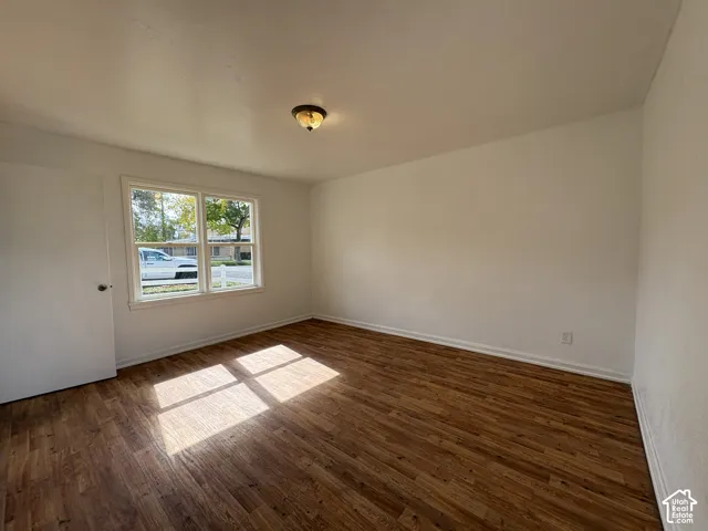 Neutral interior space featuring wood-finish flooring, white walls, flush-mount ceiling lighting, and a multi-pane window
