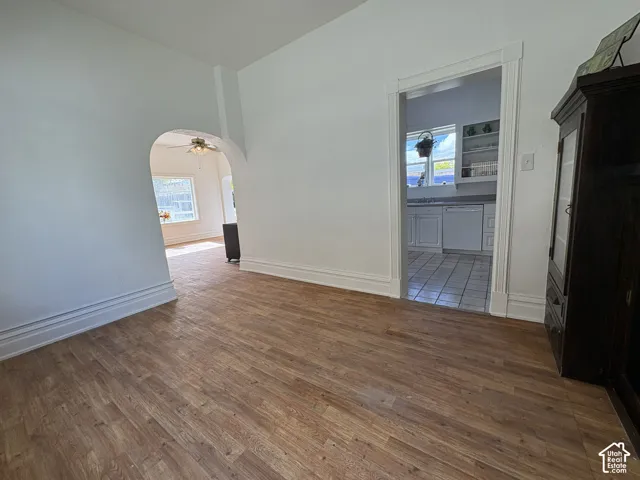 Wood-finish flooring, arched entryway, and wide white door casings