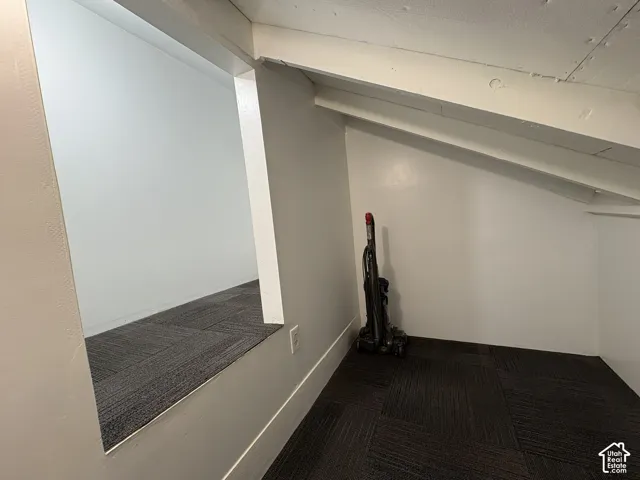 Sloped ceiling space featuring carpet tile flooring and painted wall finishes