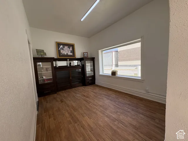 Interior space featuring wood-finish flooring, a large picture window, and built-in dark wood cabinetry with glass-paneled display doors