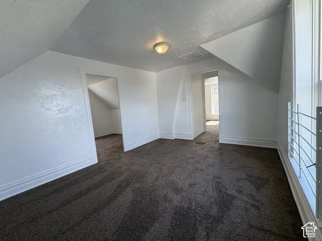 Room featuring carpeted flooring, vaulted ceilings, textured wall finishes, and recessed ceiling lighting