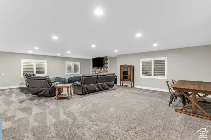 Open-concept room featuring recessed lighting, stone-veneer accent wall, patterned wall-to-wall carpeting, and windows fitted with interior shutters
