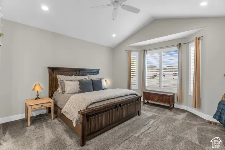Vaulted ceilings with a central fan, wall-to-wall carpeting, and a bay window featuring adjustable shutter blinds