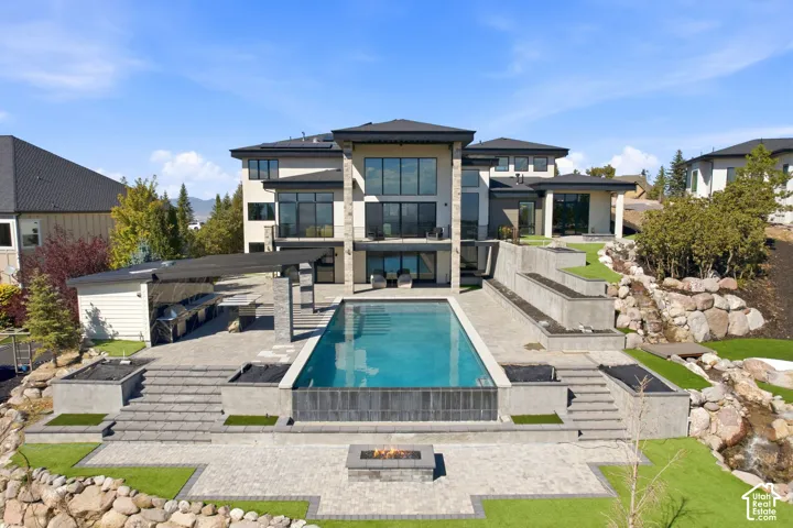 Backyard with infinty edge pool, full kitchen/BBQ, 2 gas fire pits, putting green & Tee box, and 60 ft natural stone water feature.