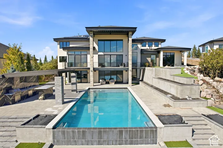 Backyard with infinty edge pool, full kitchen/BBQ, 2 gas fire pits, putting green & Tee box, and 60 ft natural stone water feature.