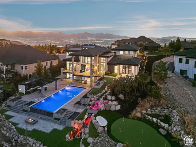 Backyard with infinty edge pool, full kitchen/BBQ, 2 gas fire pits, putting green & Tee box, and 60 ft natural stone water feature.