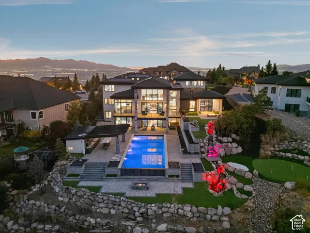 Backyard with infinty edge pool, full kitchen/BBQ, 2 gas fire pits, putting green & Tee box, and 60 ft natural stone water feature.