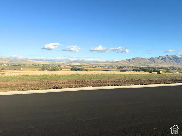 Vacant land parcel featuring paved street frontage, expansive open space, and mountain terrain backdrop
