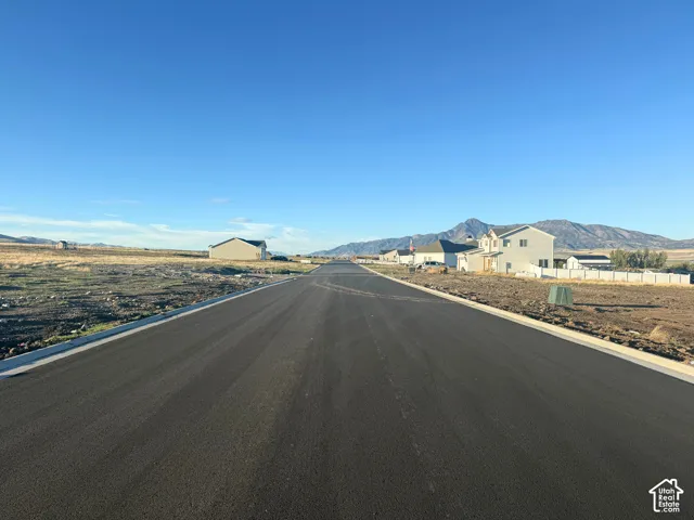Paved asphalt street featuring concrete curbing and mountain backdrops