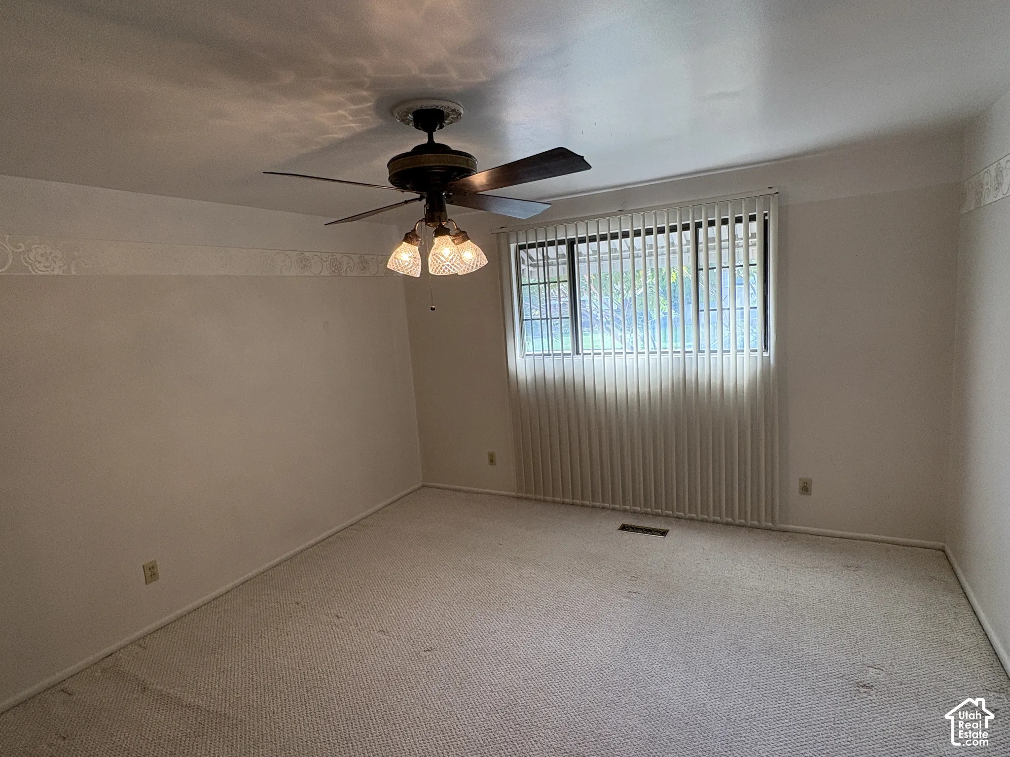 Neutral carpeting, ceiling-mounted paddle fan with multi-light fixture, and vertical window blinds