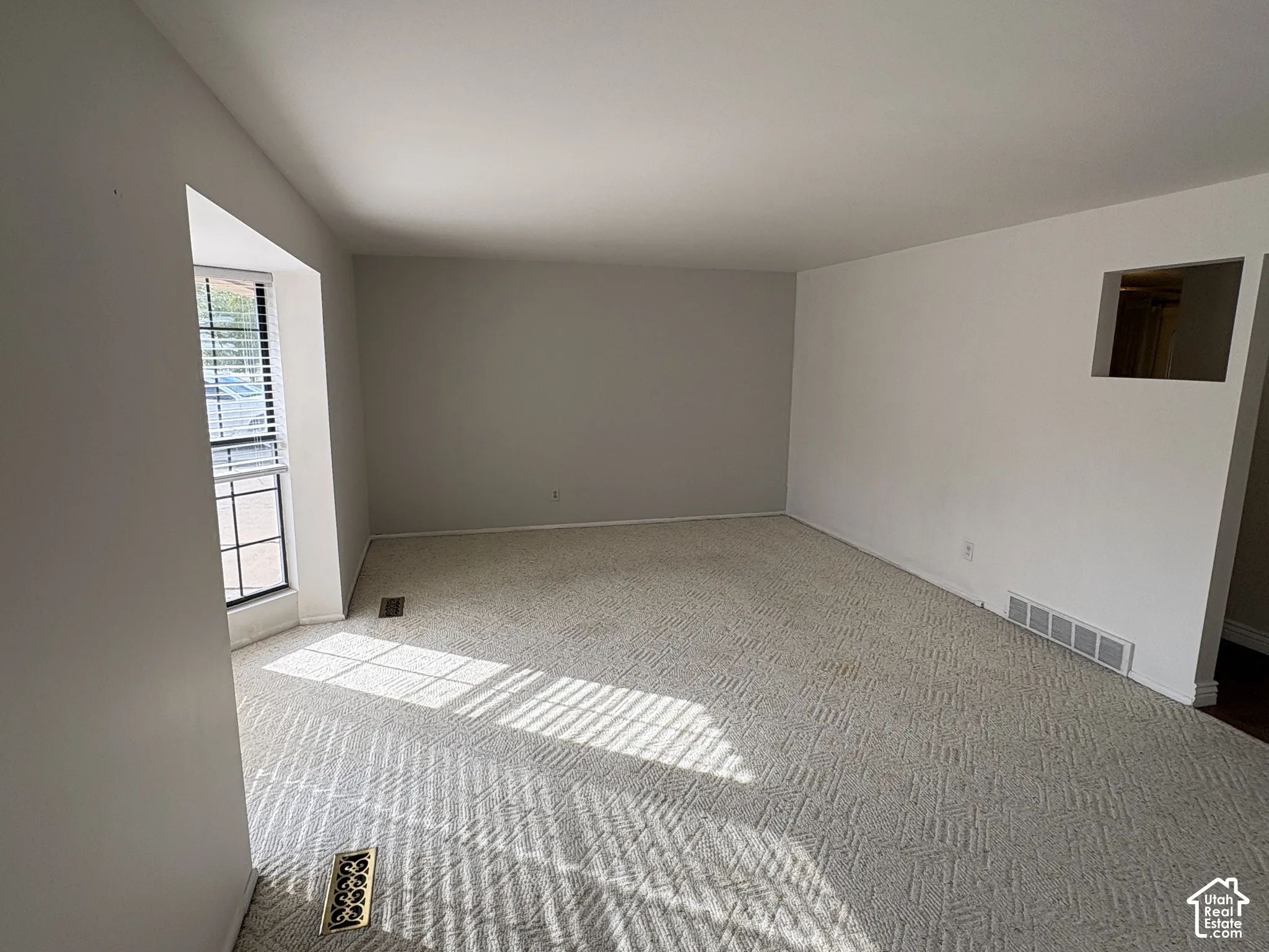 Neutral-toned carpeted flooring, window with grid detailing, and recessed wall cut-out