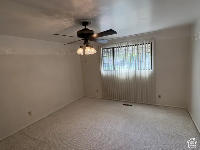 Neutral carpeting, ceiling-mounted paddle fan with multi-light fixture, and vertical window blinds