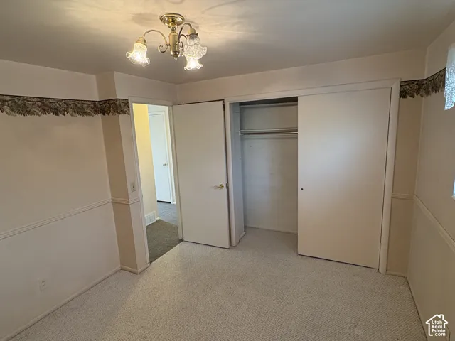 Room featuring wall-to-wall carpeting, decorative chair rail molding, ceiling-mounted multi-light fixture, and built-in closet with sliding doors