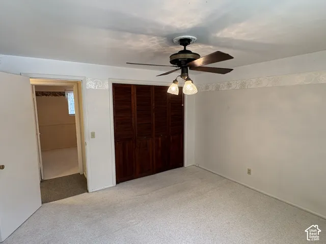 Room interior featuring wood-finish louvered closet doors, ceiling-mounted paddle fan with integrated lighting, and decorative wall border