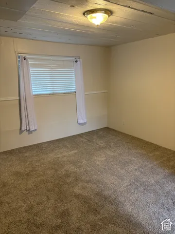 Neutral wall finishes with chair rail molding, carpeted flooring, and a flush-mount ceiling light fixture