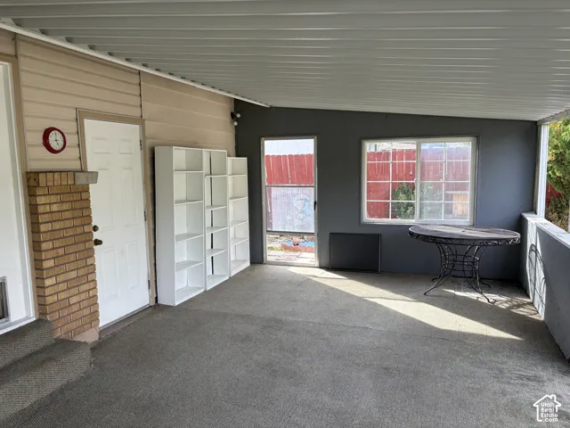 Covered patio featuring concrete flooring, a brick pillar accent, and sliding glass windows