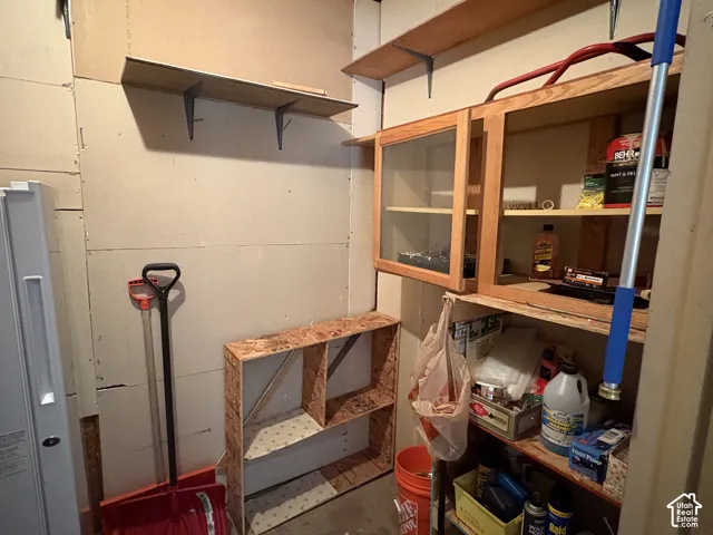 Storage space featuring wall-mounted wood shelving, built-in wooden cabinetry with glass panel doors, and fixed wooden shelving units