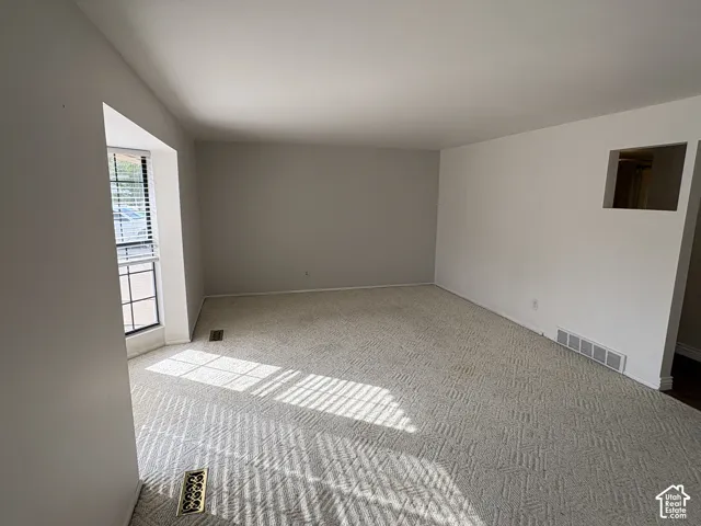 Neutral-toned carpeted flooring, window with grid detailing, and recessed wall cut-out