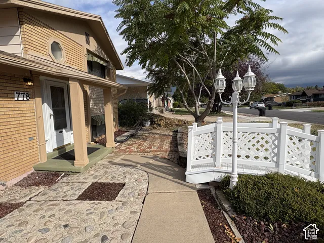 Brick exterior with a covered front porch, decorative lattice footbridge, iron post lighting, and a multi-textured stone and brick walkway