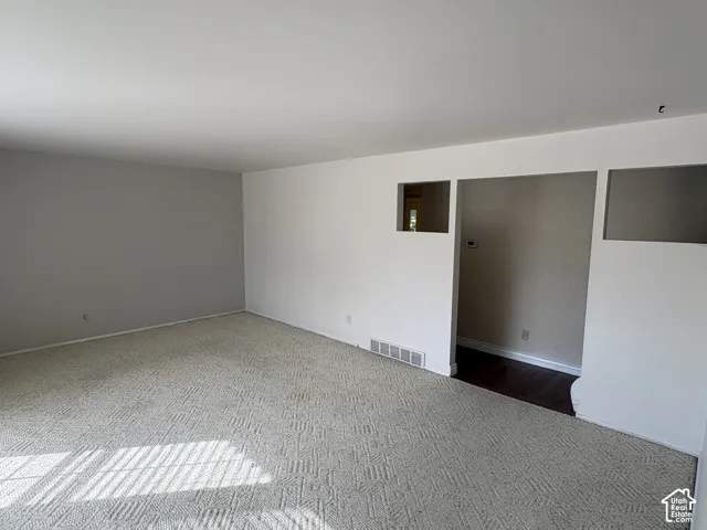 Neutral-toned interior space featuring patterned wall-to-wall carpeting, crisp white walls, and decorative rectangular wall cutouts