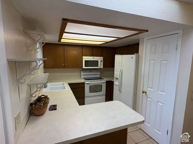 Kitchen featuring wood cabinetry, integrated lighting, white double-basin sink, laminate countertops, and built-in shelving
