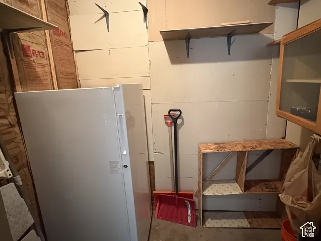 Storage area featuring wall-mounted shelving, built-in wooden cubby storage, and an integrated upright freezer